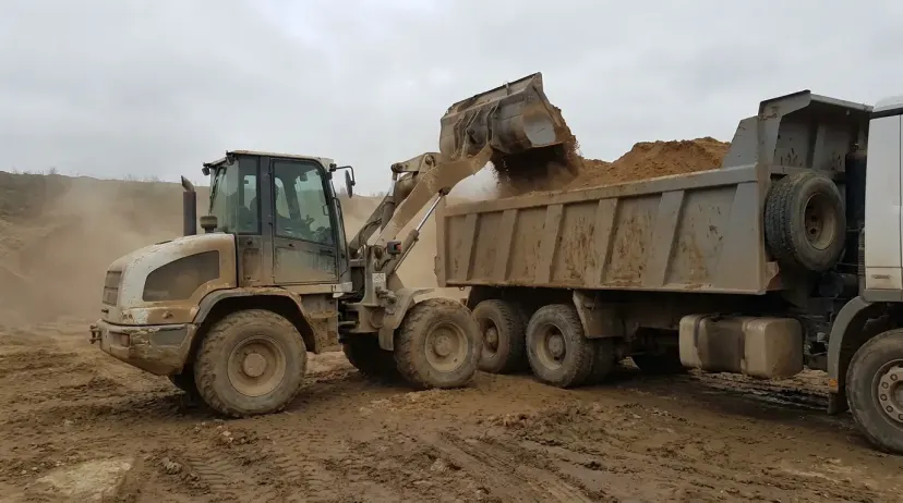carregadeira para areal carregando caminhão com areia no pátio